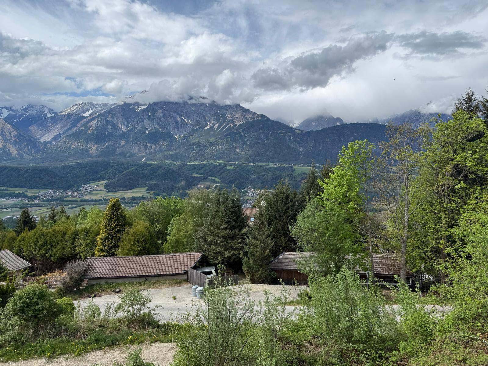 Unbebautes Grundstück mit üppiger Vegetation und einem beeindruckenden Bergpanorama im Hintergrund.