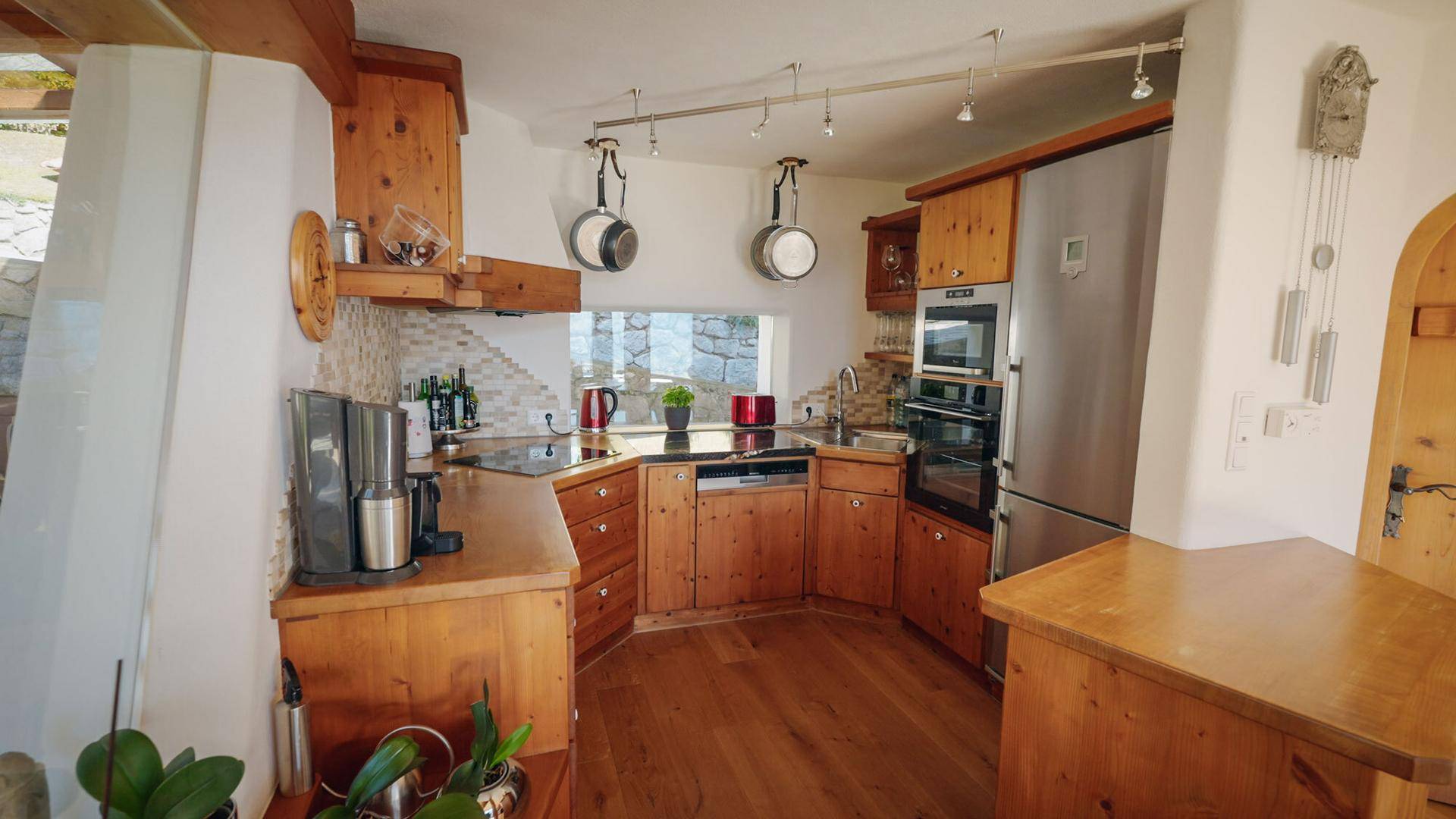 Rustikale Holzküche mit modernen Geräten, Holzboden und kleiner Fensteröffnung.