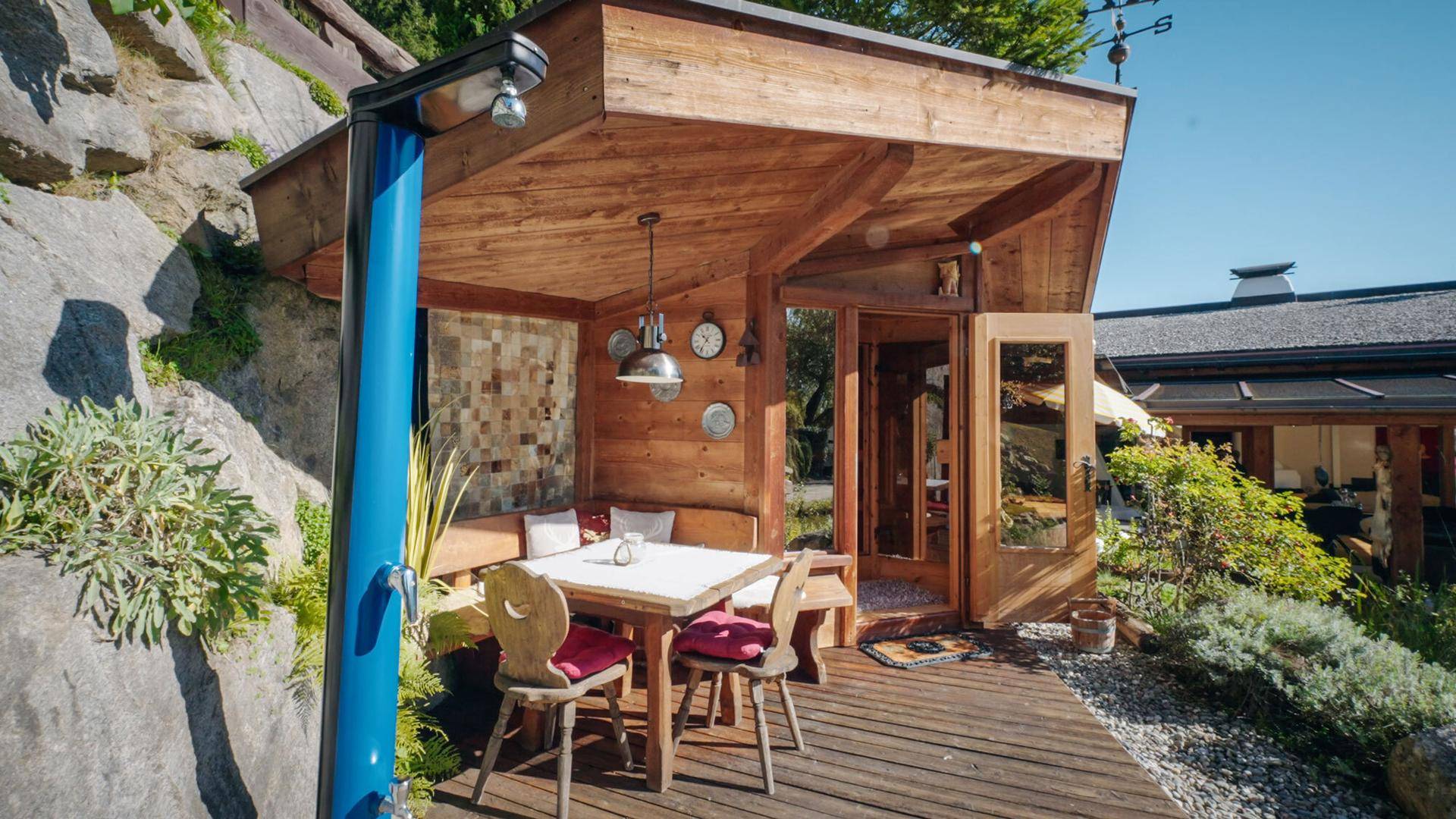 Gemütlicher Holzpavillon mit Sitzgelegenheiten und Außendusche, umgeben von Felsen.