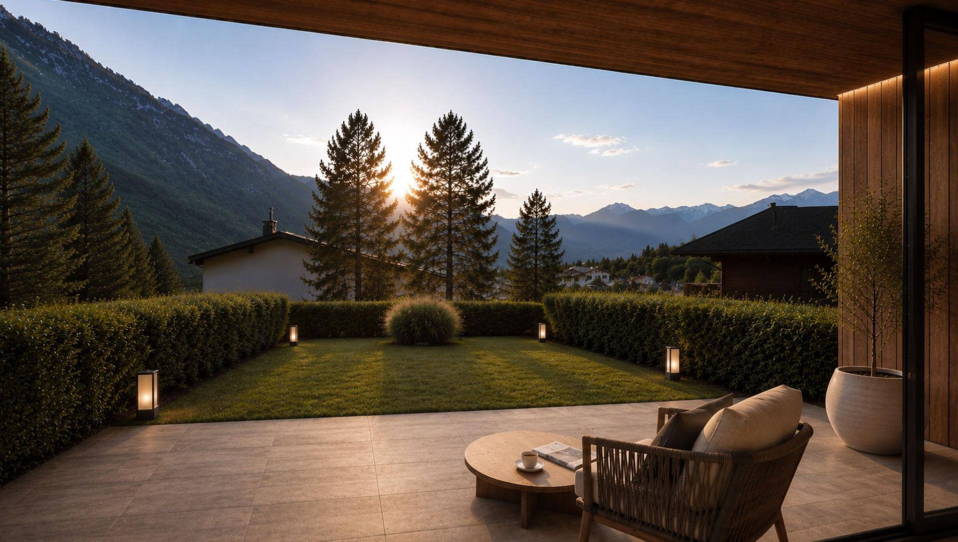 Geräumige Terrasse mit Sitzgelegenheiten, Rasenfläche und Blick auf die Berge bei Sonnenuntergang.