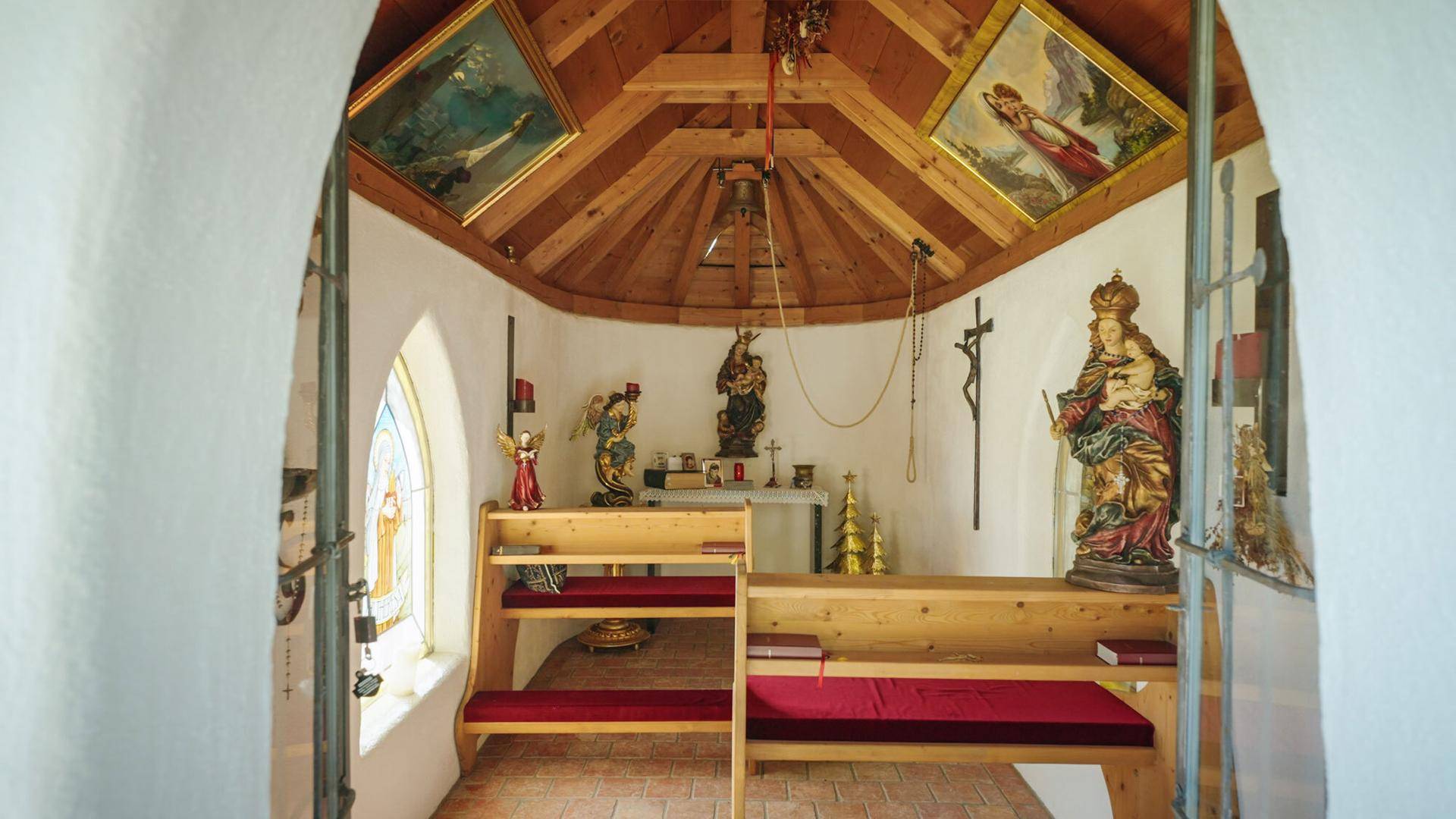 Kleine, liebevoll gestaltete Kapelle mit Holzbänken und religiösen Figuren.