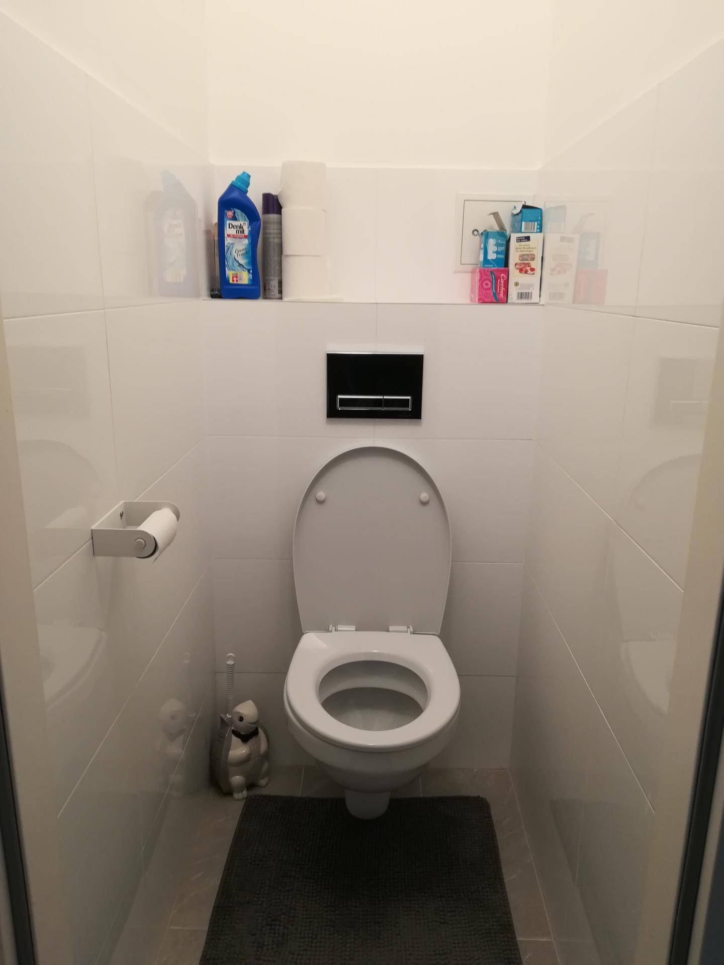 Kompaktes Gäste-WC mit Wand-WC und weißen Fliesen an den Wänden.