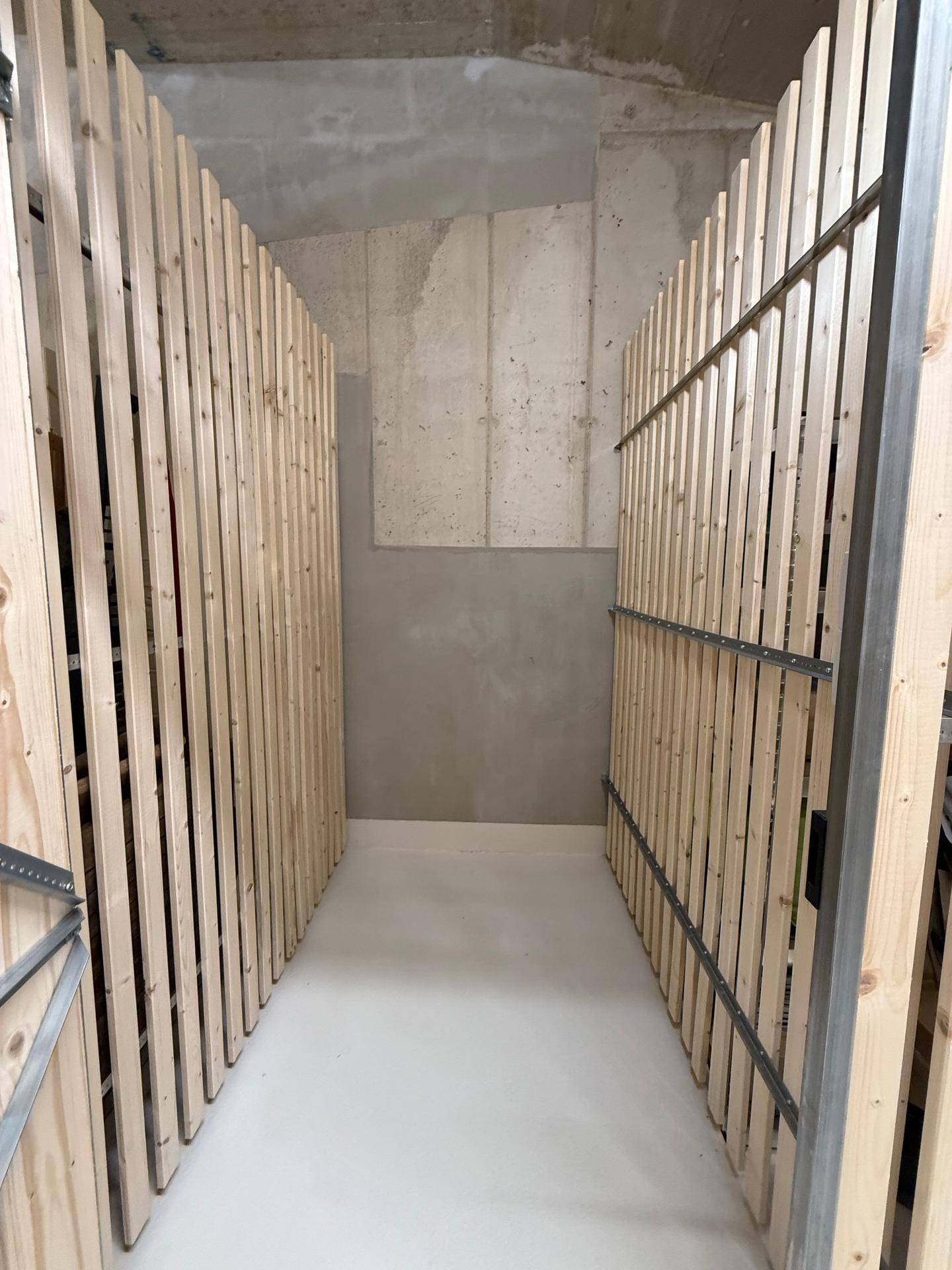 Kellerabteil mit Holzlattenwänden für zusätzlichen Stauraum im Untergeschoss.