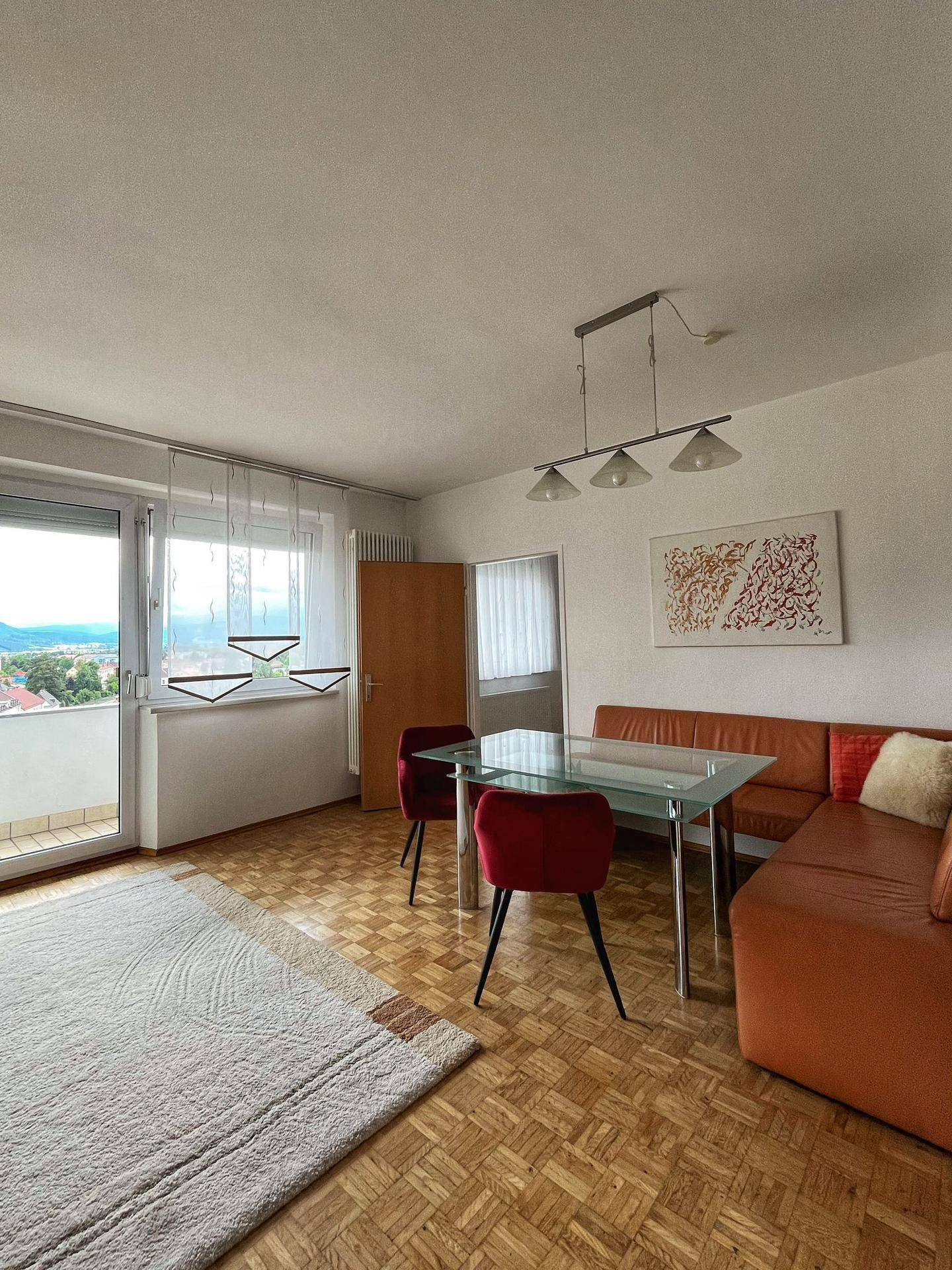 Heller Wohn- und Essbereich mit Glastisch, Eckbank und Zugang zum Balkon.