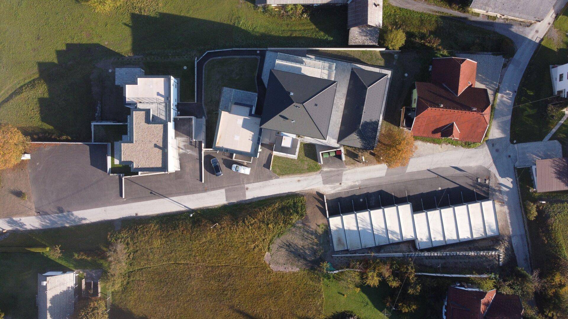 Draufsicht aus der Luft auf die Wohnanlage mit Gebäuden, Parkplätzen und Grünflächen.