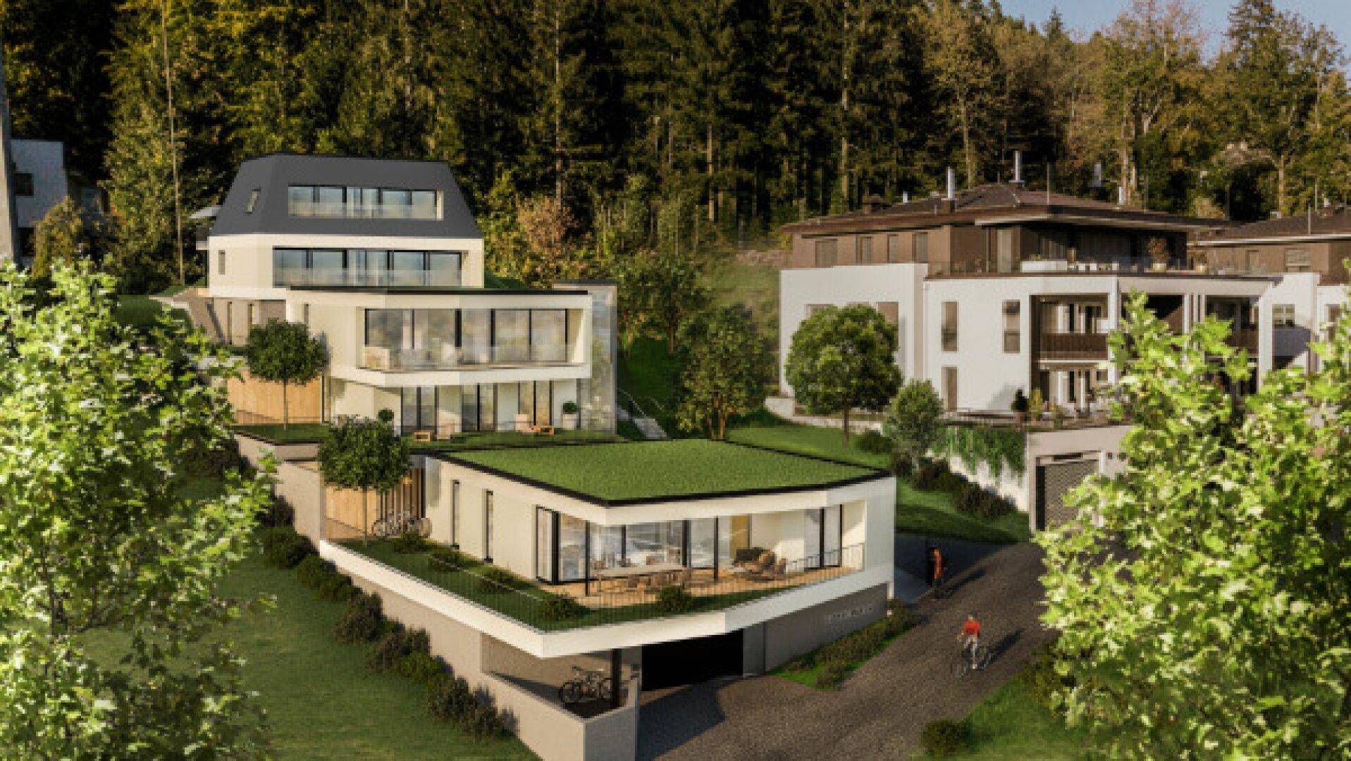 Gesamtansicht einer modernen Wohnanlage mit mehreren Gebäuden in einer grünen Hügellandschaft.