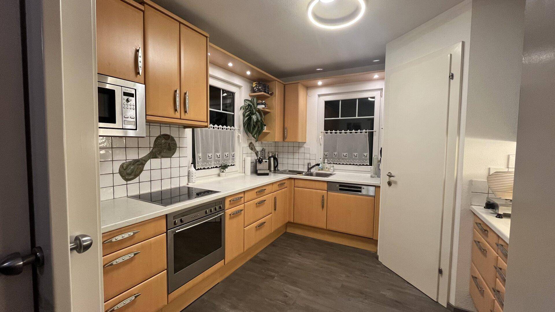Gemütliche Küche mit hellen Holzschränken, modernen Geräten und Fliesenrückwand.