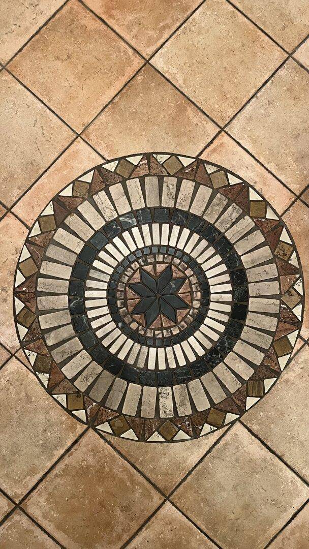 Detailaufnahme eines dekorativen Fliesenmosaiks auf dem Boden.