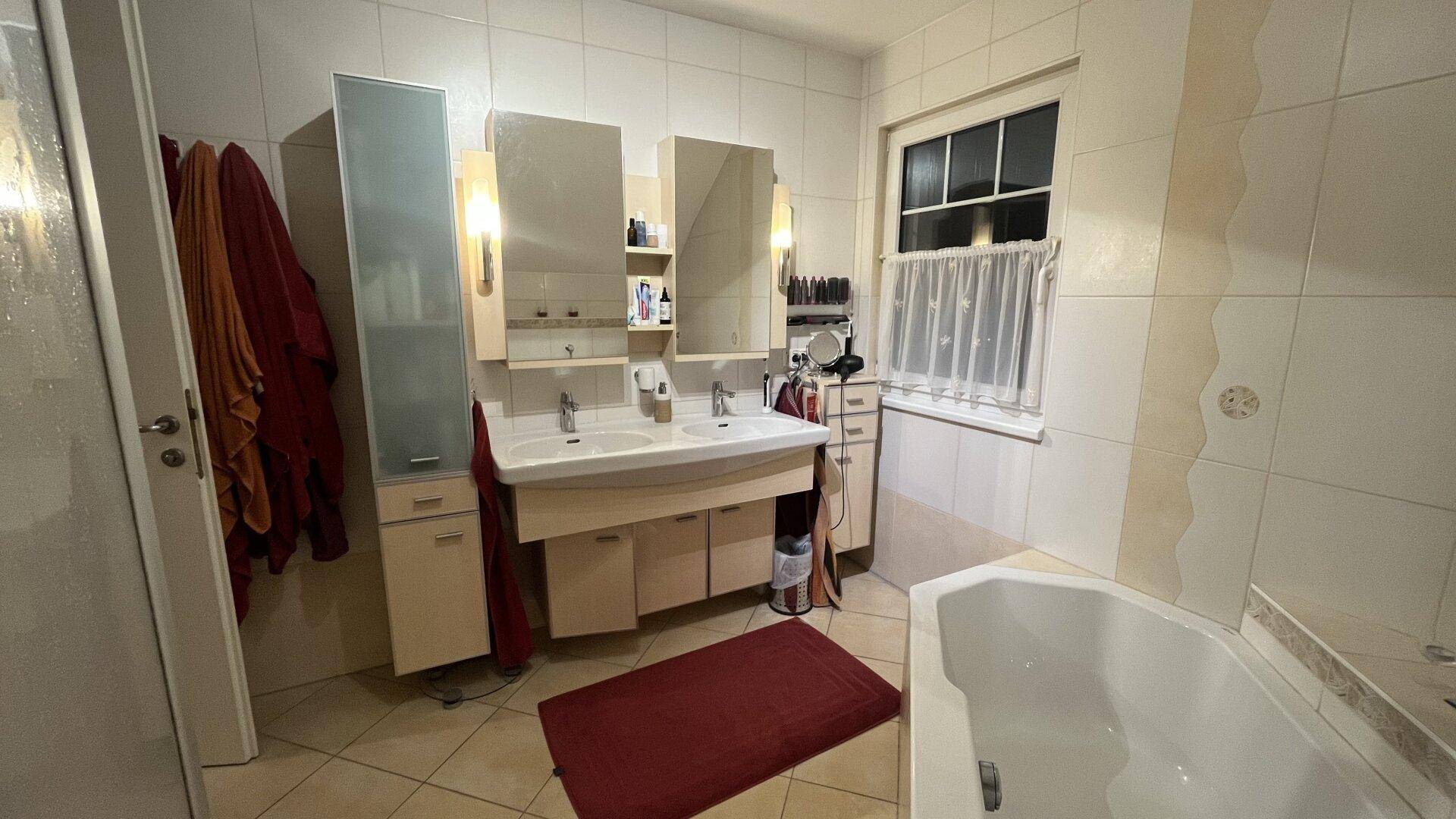 Geräumiges Badezimmer mit Doppelwaschbecken, Spiegelschränken und Badewanne.