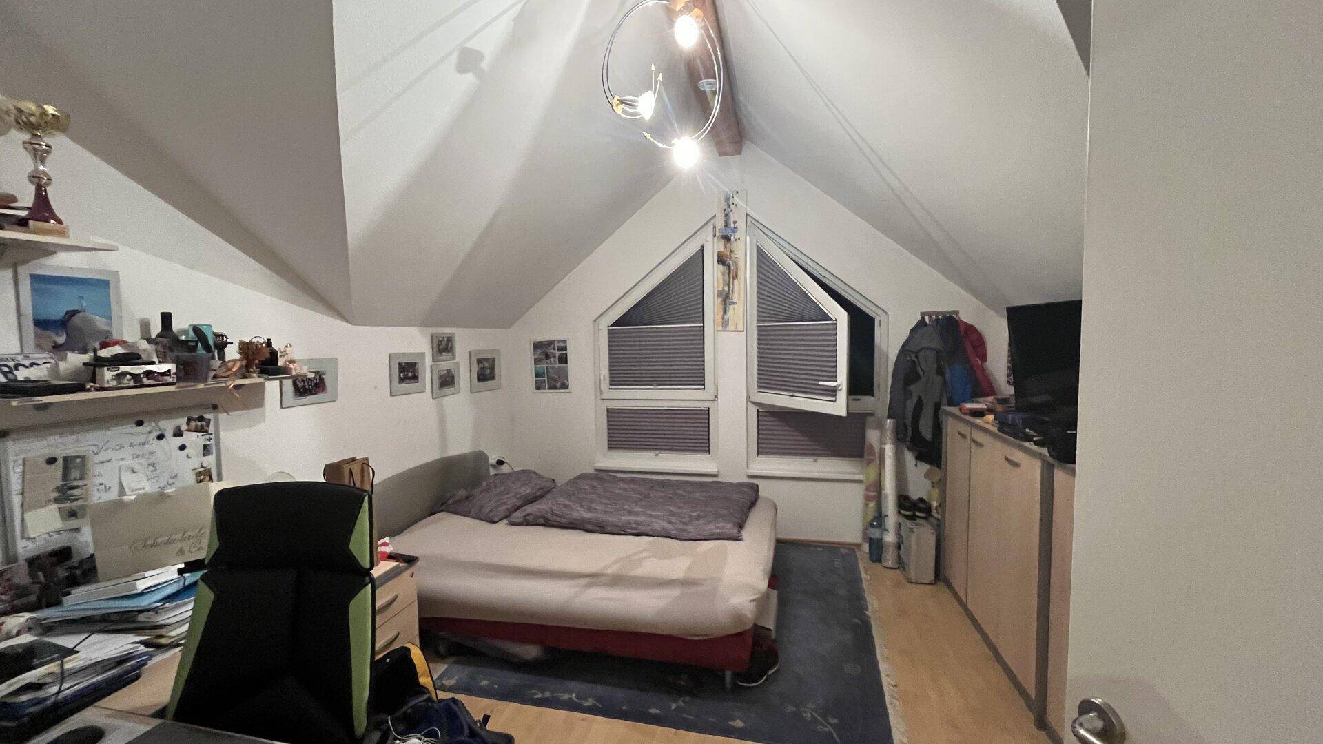 Gemütliches Schlafzimmer im Dachgeschoss mit schrägen Wänden und Dachfenstern.