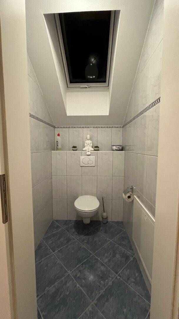 Kleines Gäste-WC im Dachgeschoss mit Dachfenster und blauen Bodenfliesen.