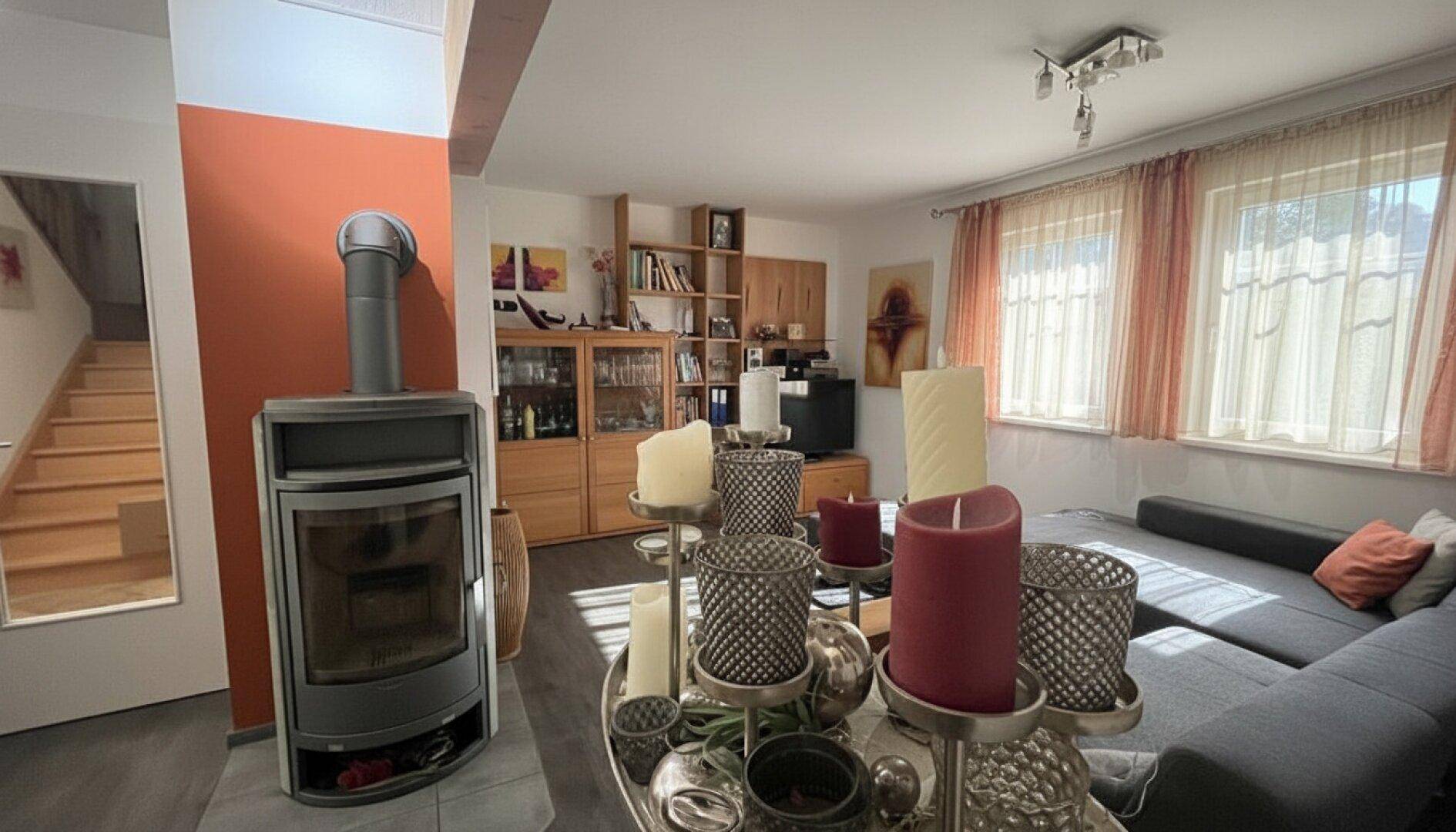 Wohnzimmer mit Kaminofen, gemütlicher Sitzecke und Blick auf die Treppe.