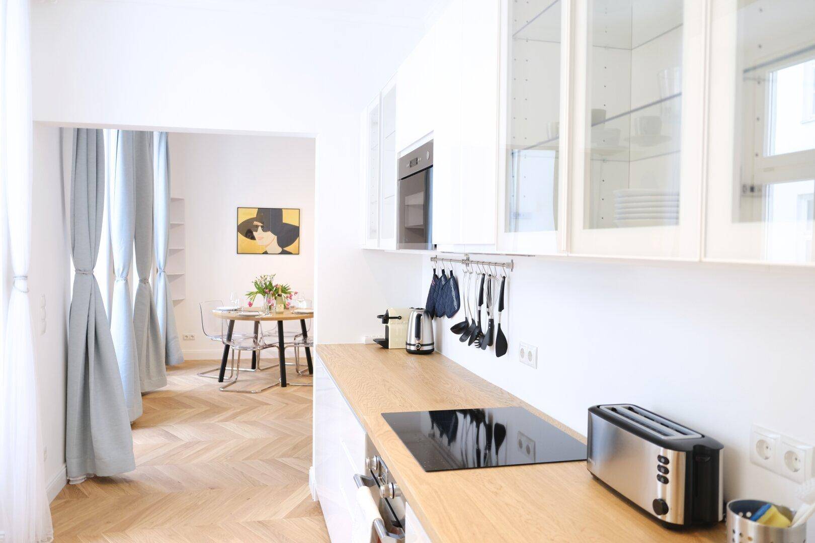 Moderne Küche mit Holzarbeitsplatte, Induktionskochfeld und Blick auf den Essbereich.