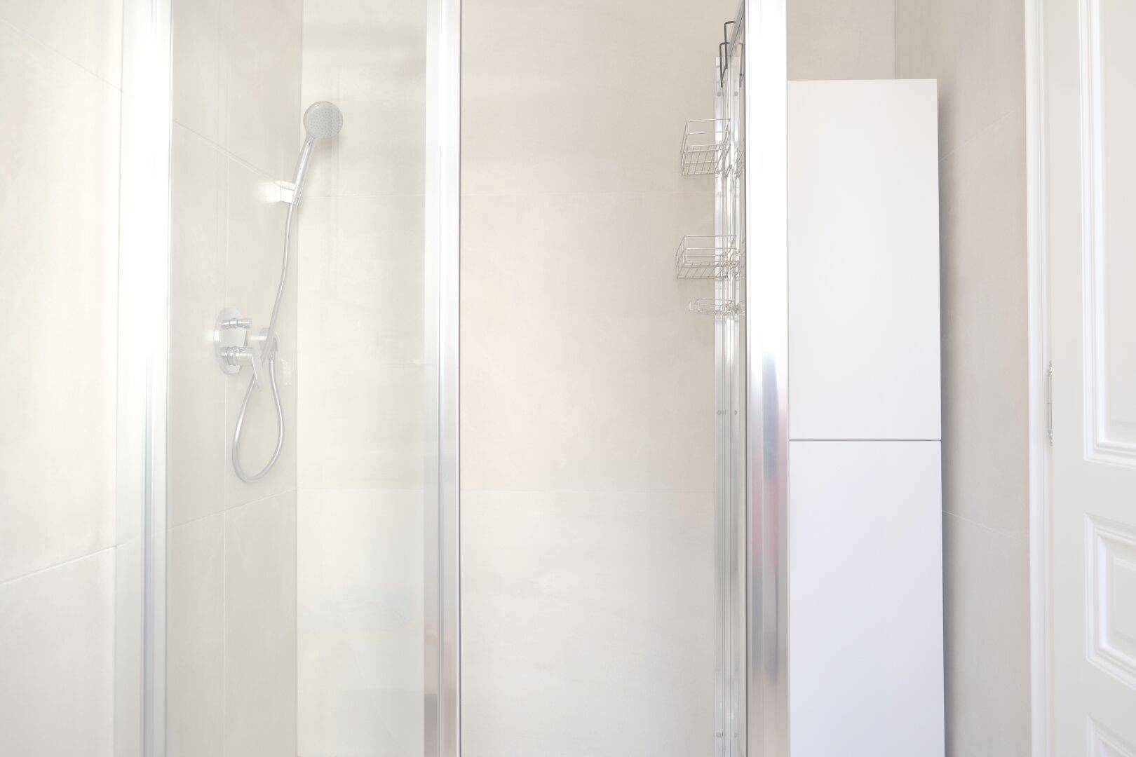 Duschbereich im modernen Badezimmer mit Glasabtrennung und hellen Wandfliesen.