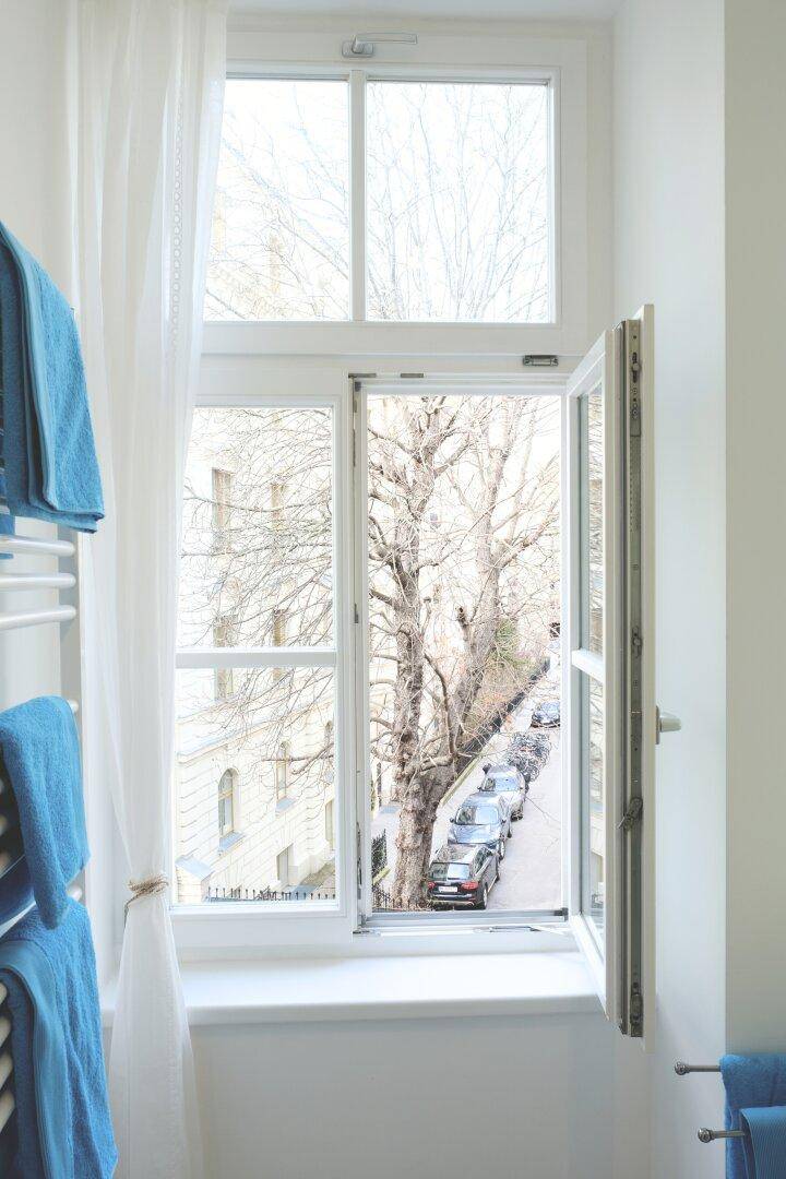 Badezimmer mit großem Fenster, das viel Tageslicht hereinlässt und Blick auf die Straße bietet.