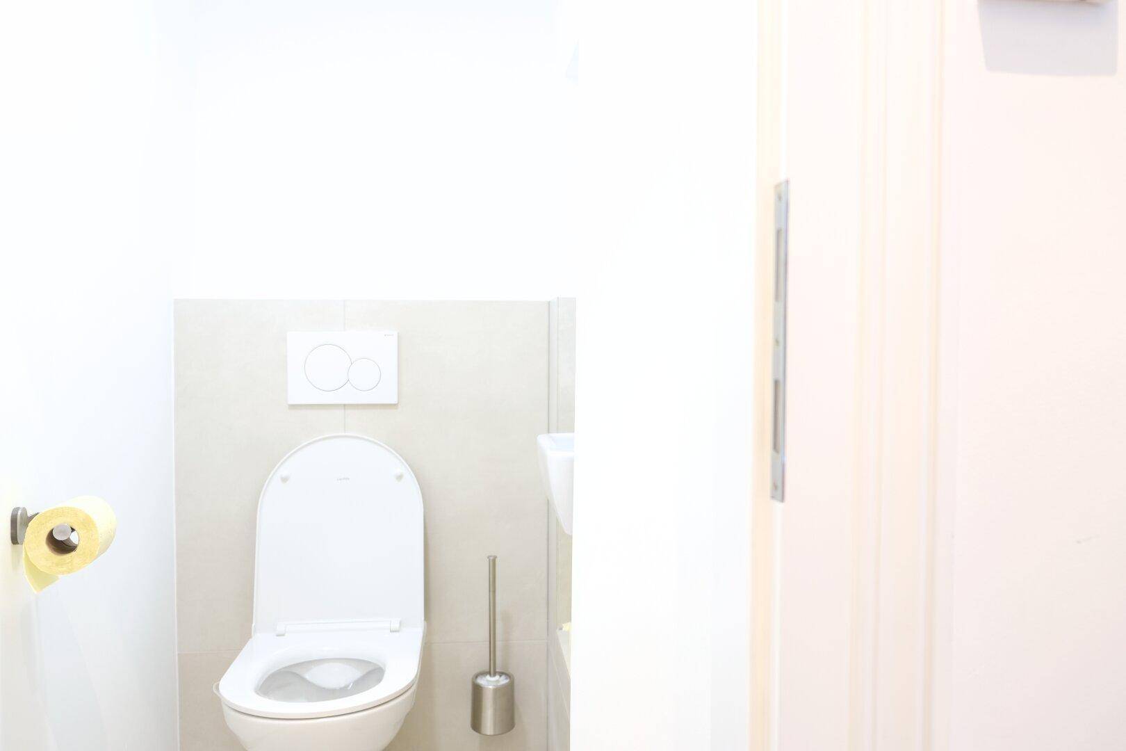 Separate Toilette mit wandmontiertem WC und minimalistischem Design in hellem Raum.