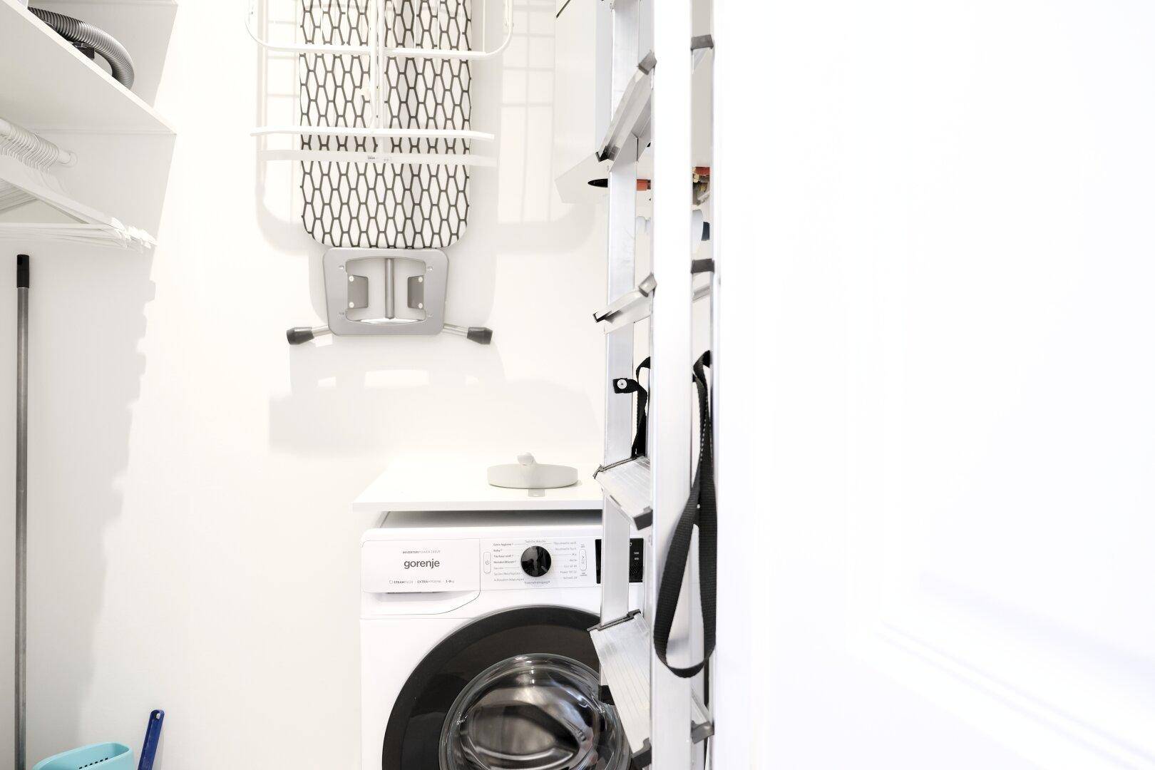 Praktischer Hauswirtschaftsraum mit Waschmaschine, Bügelbrett und Regalsystem.
