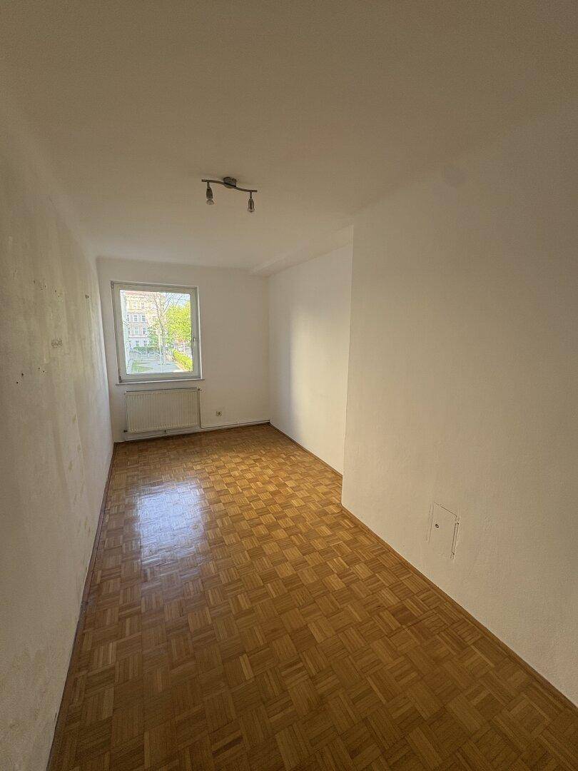 Helles, leeres Zimmer mit Parkettboden und Blick auf die Umgebung, bietet viel Potenzial für Einrichtungsideen.