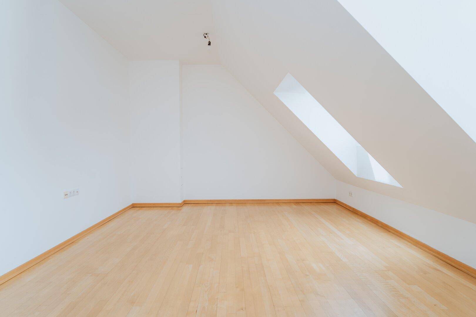 Ruhiger Eckbereich im Dachgeschoss mit Holzboden und schräger Decke.