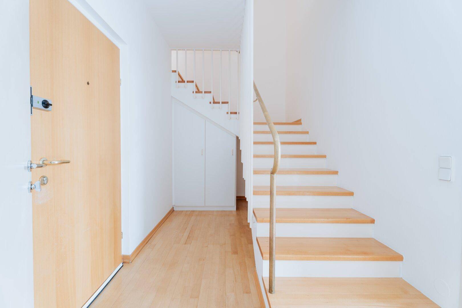Eingangsbereich mit Holzboden, Holztreppe und modernem Treppengeländer.