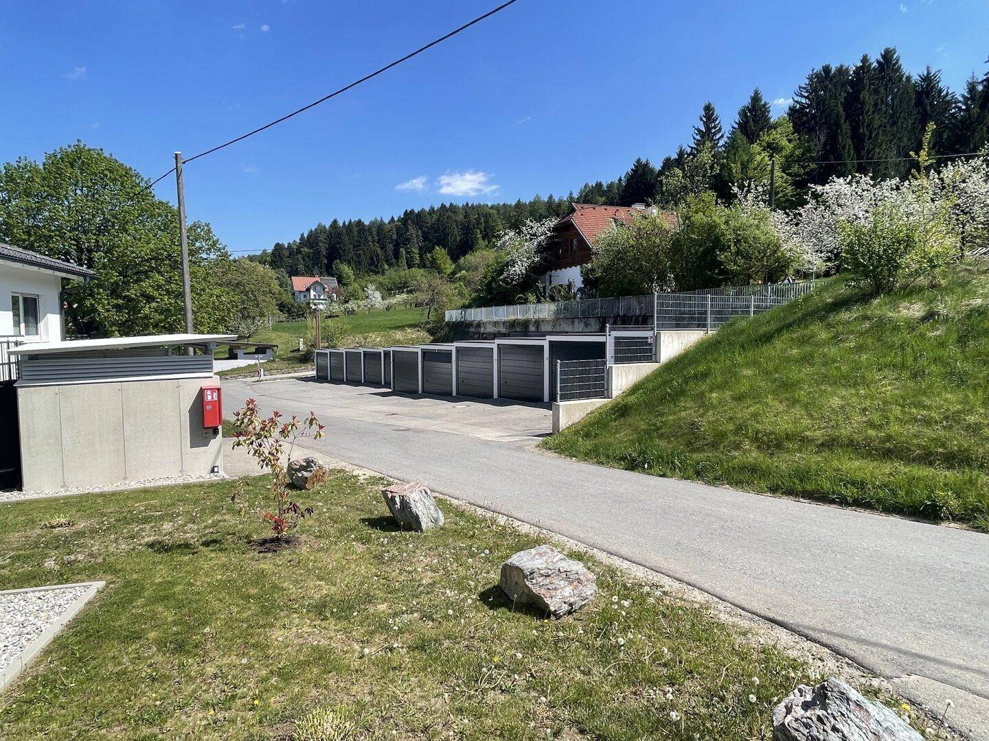 Außenparkplätze am Fuße eines bewaldeten Hügels mit viel Grün in der Umgebung.