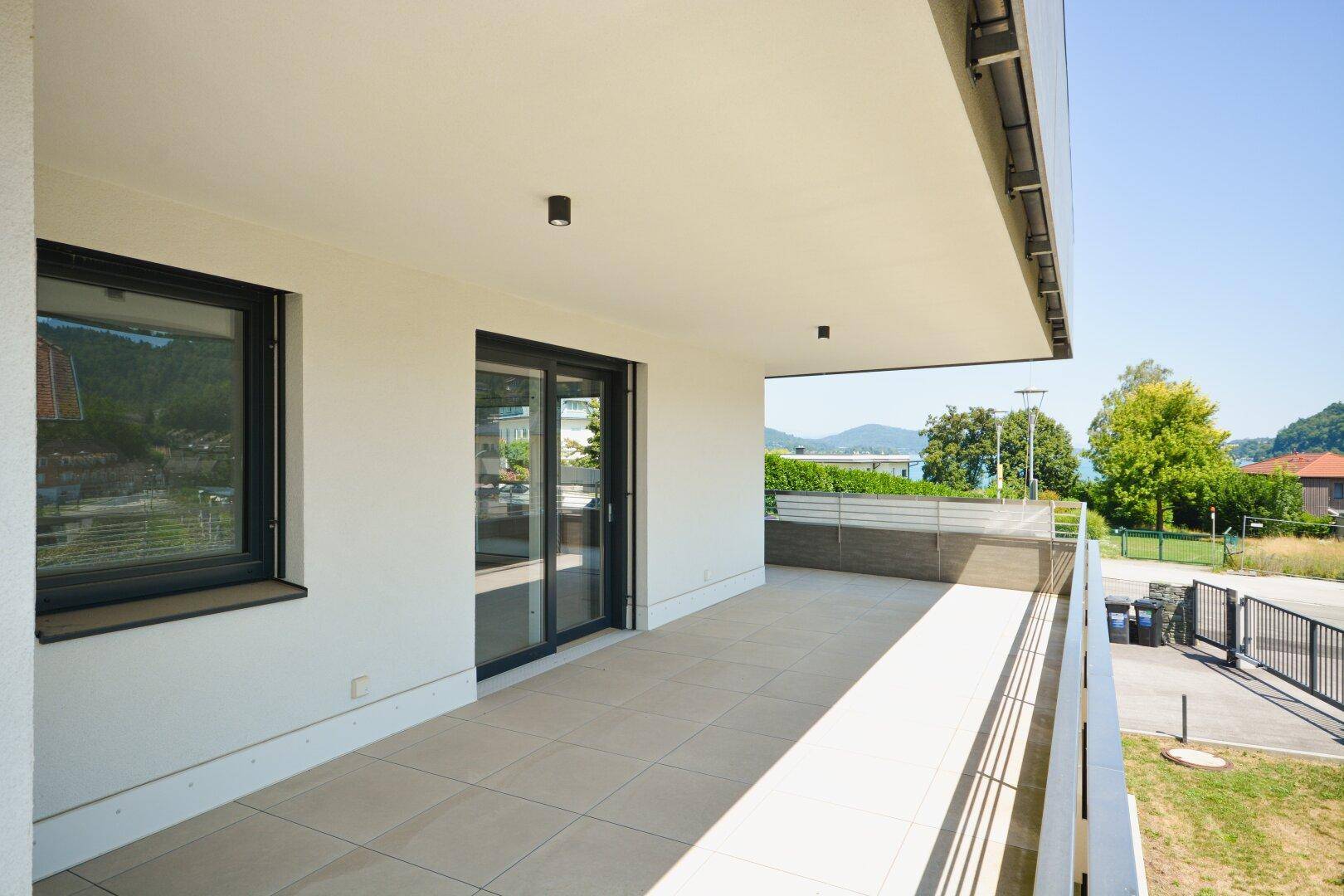 Helle, weitläufige Terrasse mit Fliesenboden und Blick auf die Umgebung und Berge.