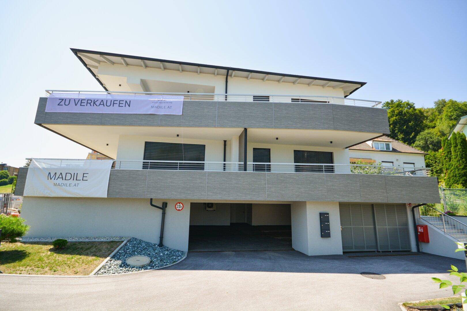Neubau-Wohngebäude mit modernen Balkonen und Zugang zur Tiefgarage, zum Verkauf angeboten.