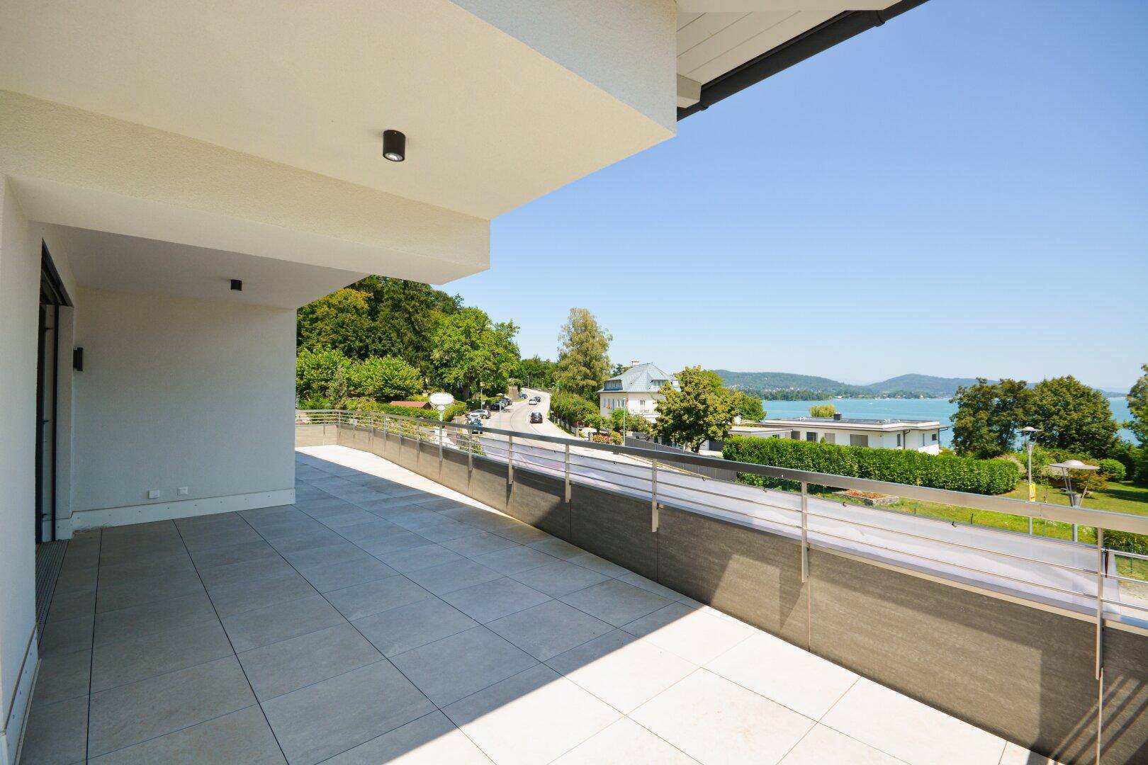 Großzügige, geflieste Terrasse mit weitem Blick auf den See und die umliegende grüne Landschaft.