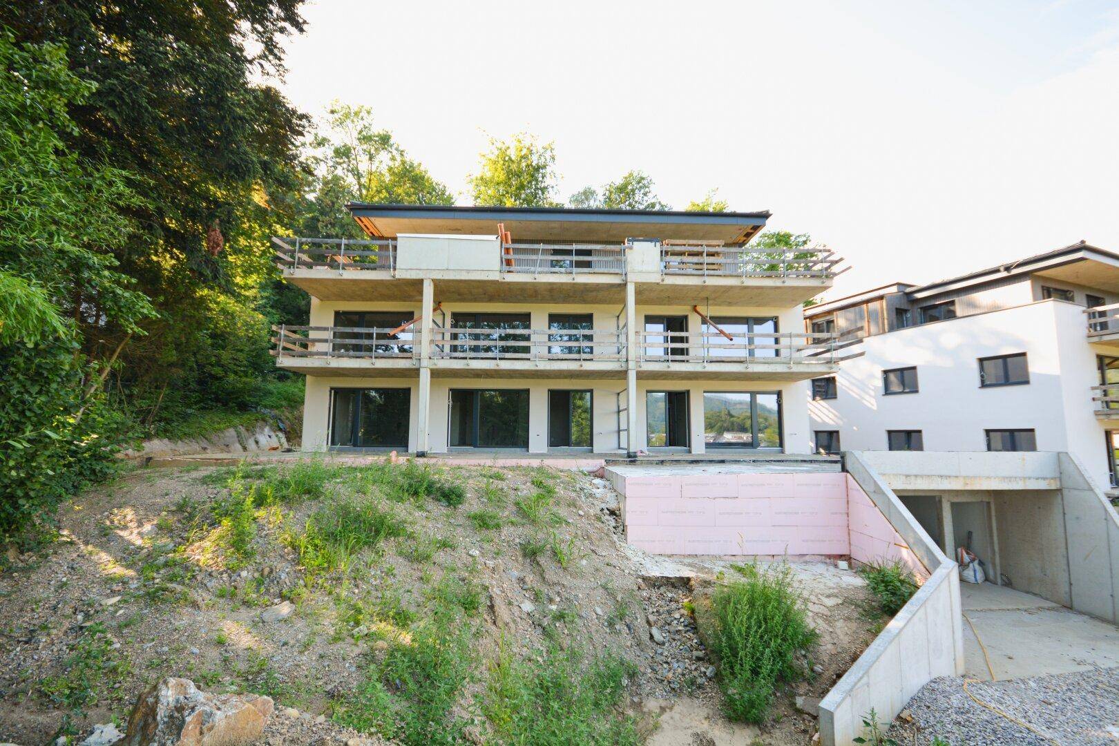 Neubauprojekt mit mehreren Wohneinheiten und großzügigen Balkonen in Hanglage.