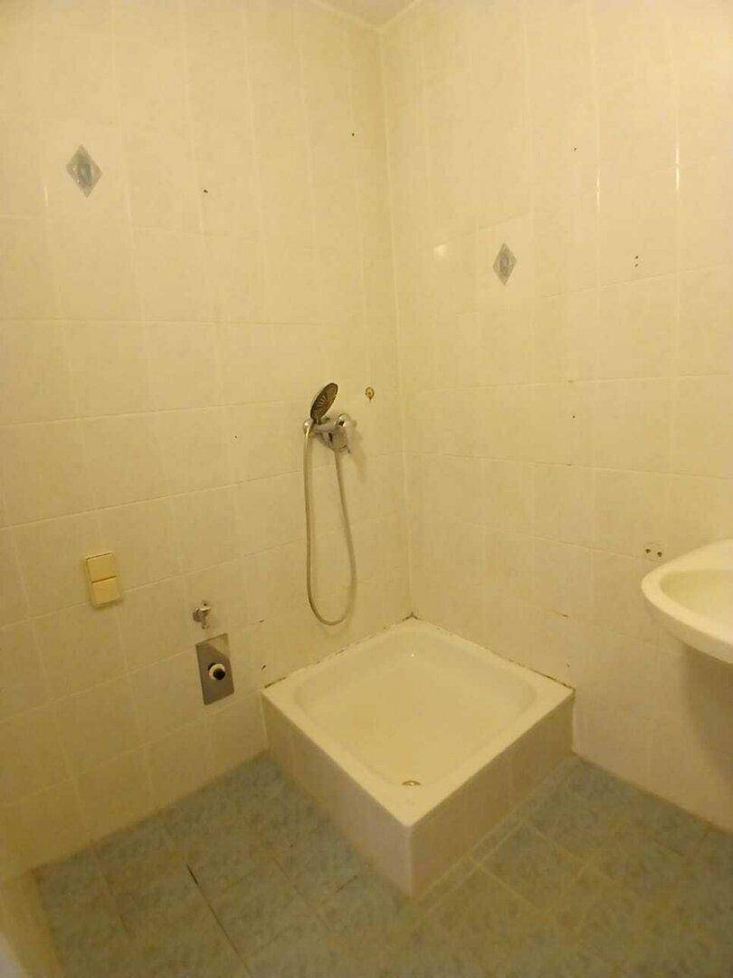 Duschbereich im Badezimmer mit hellen Fliesen und einer einfachen Duschwanne, praktisch und sauber.