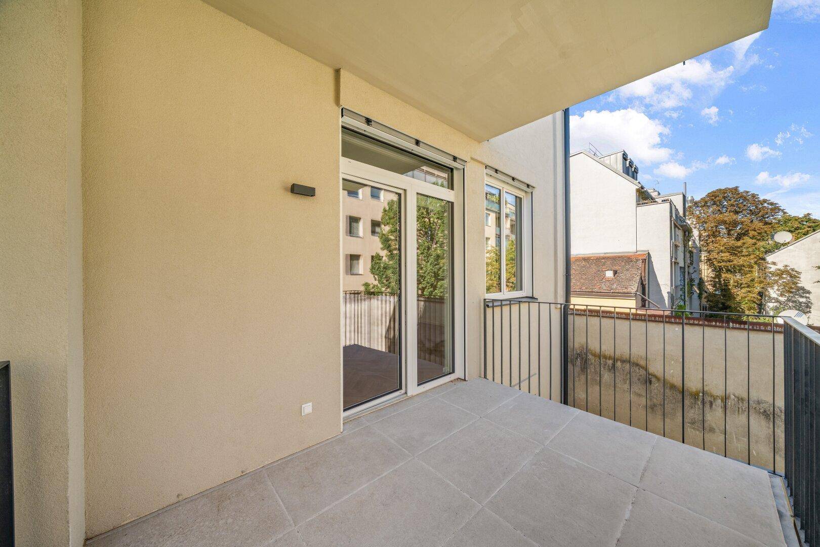 Geräumiger Balkon mit Fliesenboden und Blick auf die umliegenden Gebäude.