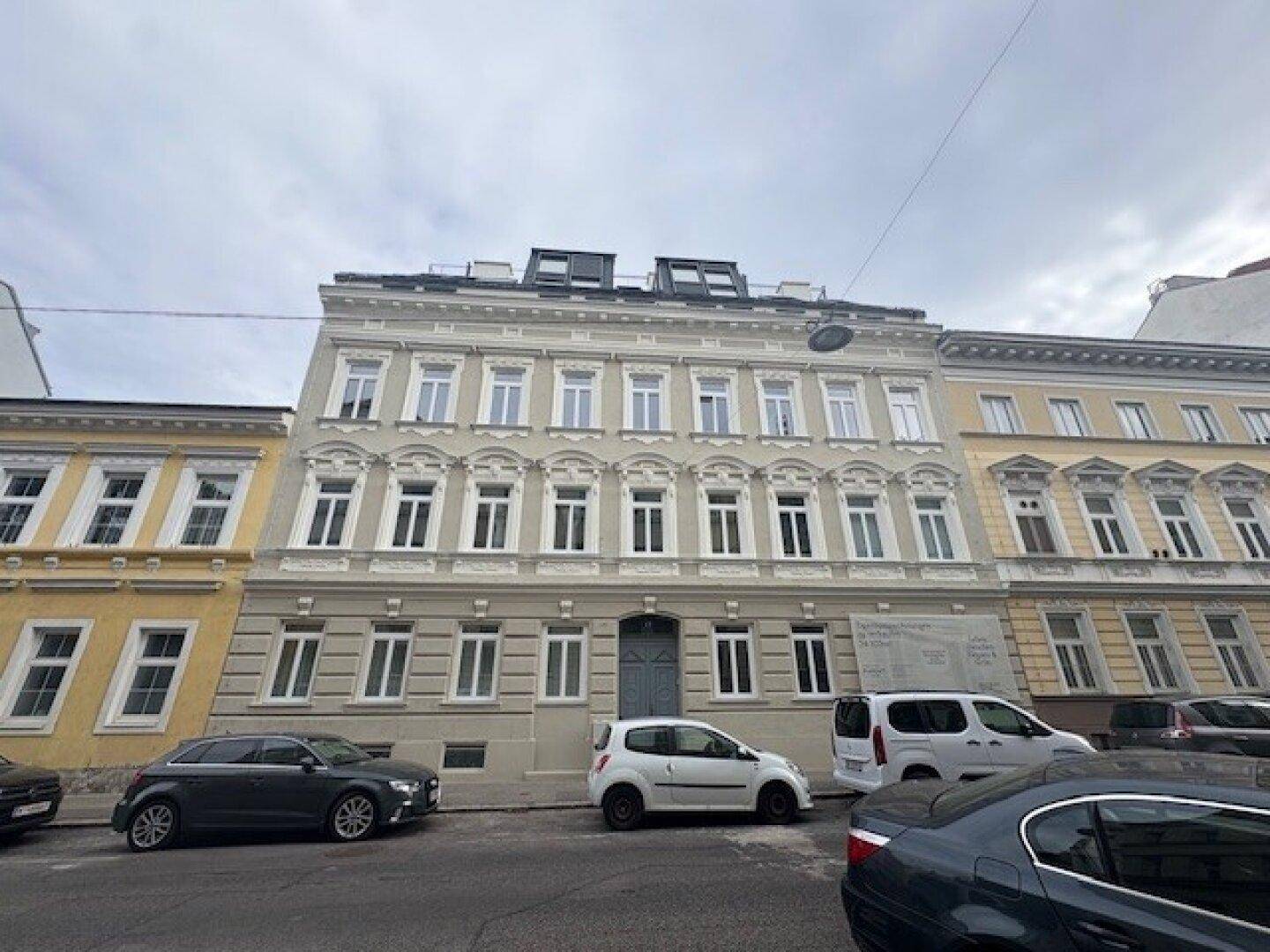 Historisches Gebäude mit klassischer Fassade und vielen Fenstern an einer städtischen Straße.