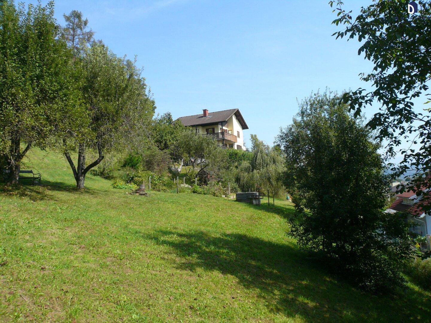 Das Wohnhaus ist von einem großen, grünen Garten mit Obstbäumen und Rasenflächen umgeben.