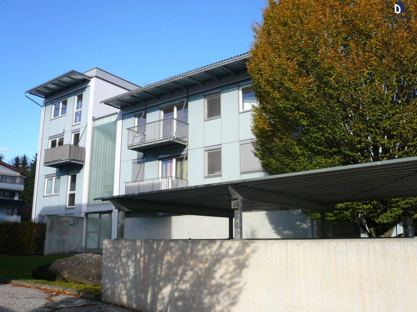Modernes Mehrfamilienhaus mit Carport und grüner Umgebung.
