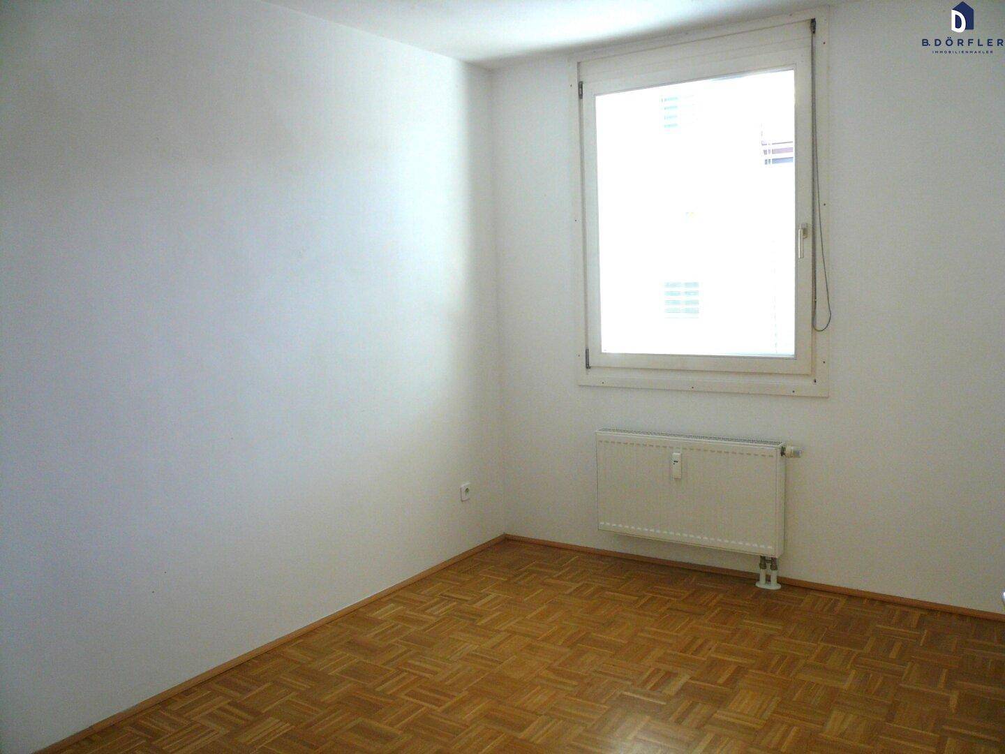 Lichtdurchfluteter Raum mit Parkettboden und großem Fenster.