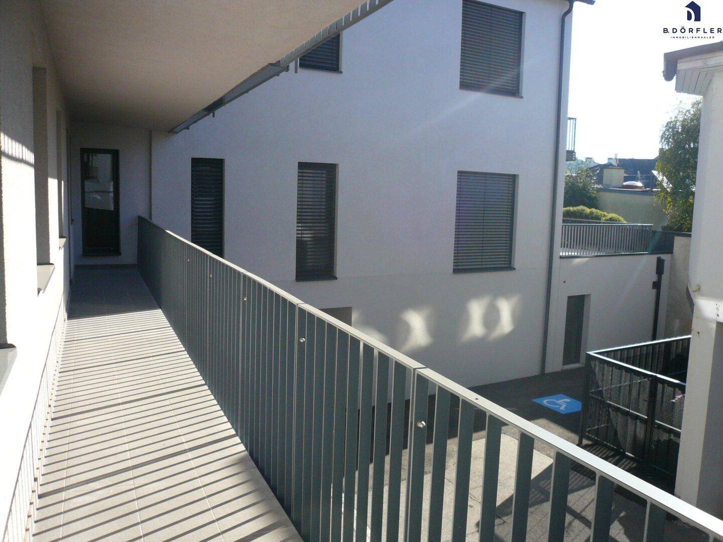 Außenansicht eines Gebäudes mit barrierefreier Rampe und Fensterläden.