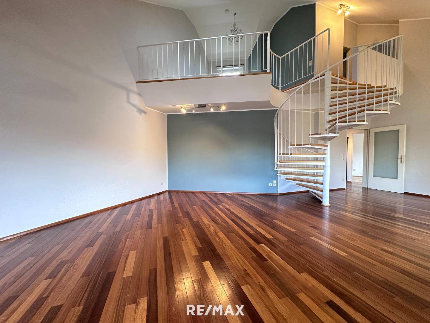 Großzügiger Wohnraum mit beeindruckender Wendeltreppe, die zur oberen Etage führt.