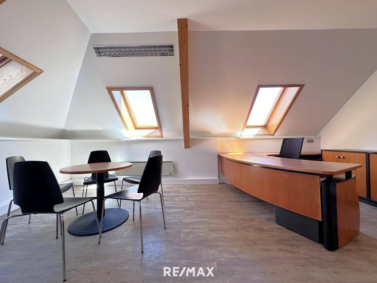 Großzügiges Büro im Dachgeschoss mit mehreren Arbeitsplätzen, Dachfenstern und Holzbalken, bietet viel Tageslicht.