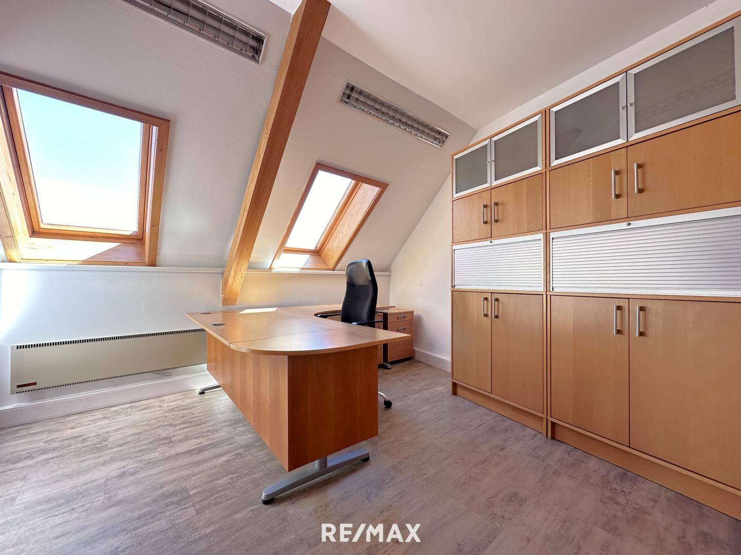 Helles Büro im Dachgeschoss mit schrägen Wänden, Dachfenstern und funktionalen Holzmöbeln, ideal für konzentriertes Arbeiten.