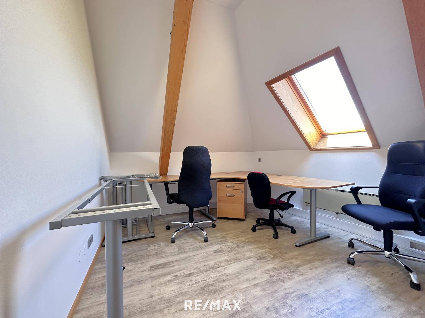 Funktionales Büro im Dachgeschoss mit mehreren Schreibtischen, Bürostühlen und einem Dachfenster für gute Belichtung.