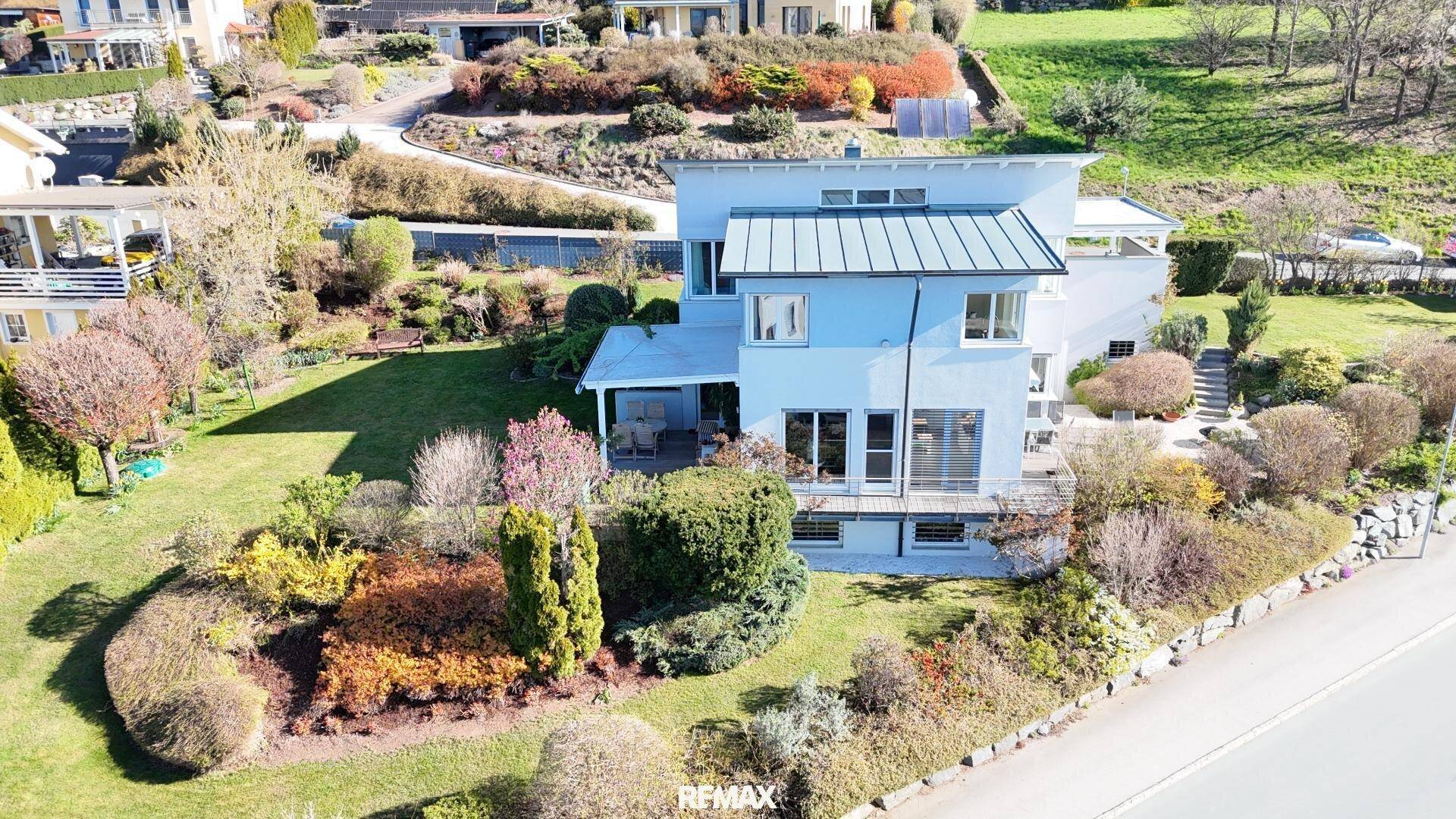 Haus in Hanglage mit mehreren Terrassen und einem üppigen, mehrstufigen Gartenbereich.