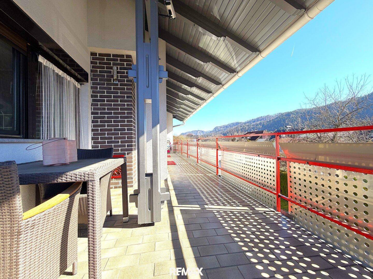 Langer Balkon mit Sitzgelegenheiten und weitem Blick auf die Berglandschaft.