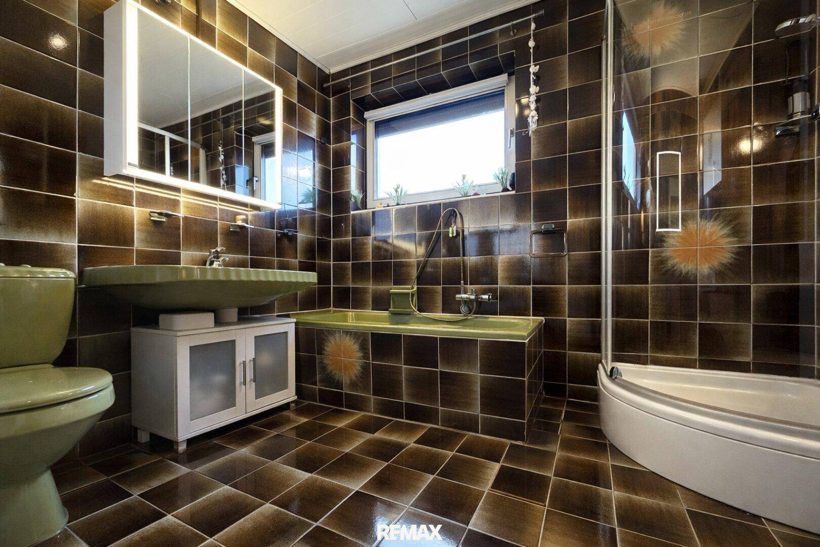 Badezimmer im Stil der 80er Jahre mit braunen Fliesen, grüner Keramik und Duschkabine.
