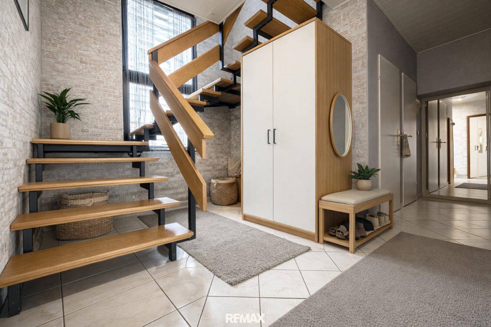 Heller Eingangsbereich mit Holztreppe, Fliesenboden und praktischem Garderobenschrank.