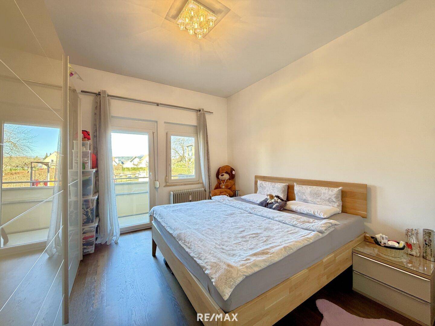 Gemütliches Schlafzimmer mit Holzbett, großem Kleiderschrank und Zugang zu einem Balkon.