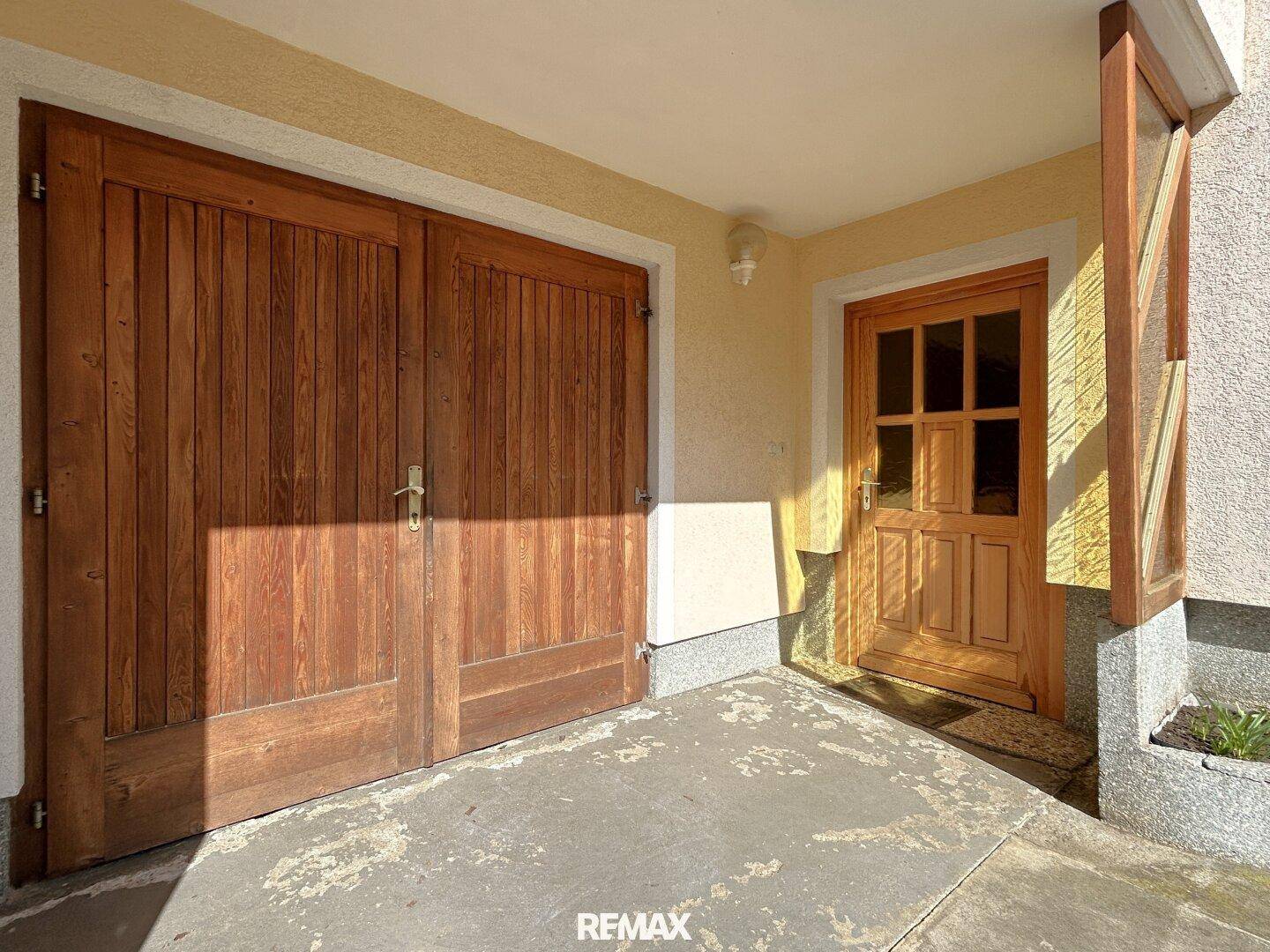 Eingangsbereich mit rustikalen Holztüren für Garage und Haupteingang des Hauses.