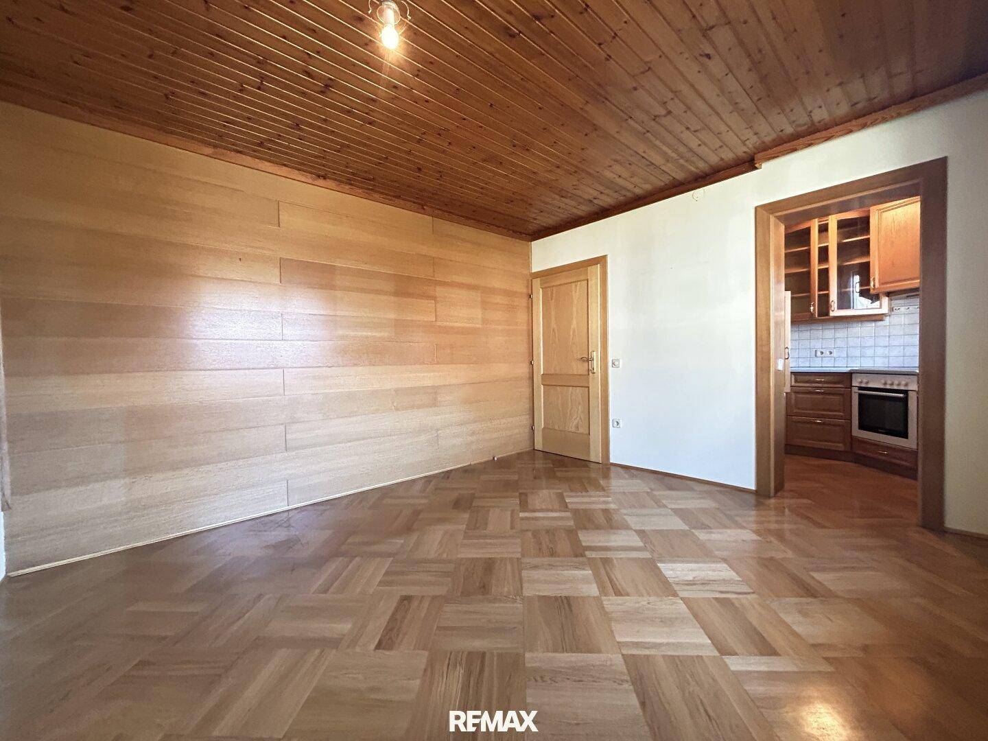 Geräumiges Wohnzimmer mit Parkettboden, Holzdecke und Holzwandverkleidung.