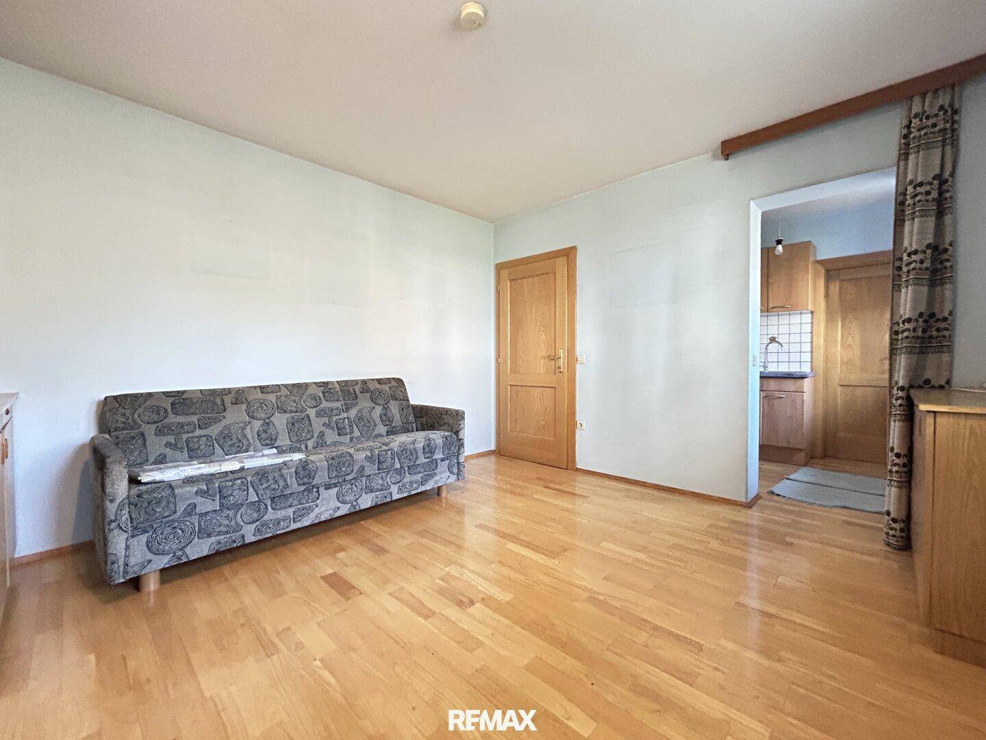 Helles Wohnzimmer mit Parkettboden und einem Sofa, bereit zur individuellen Gestaltung.