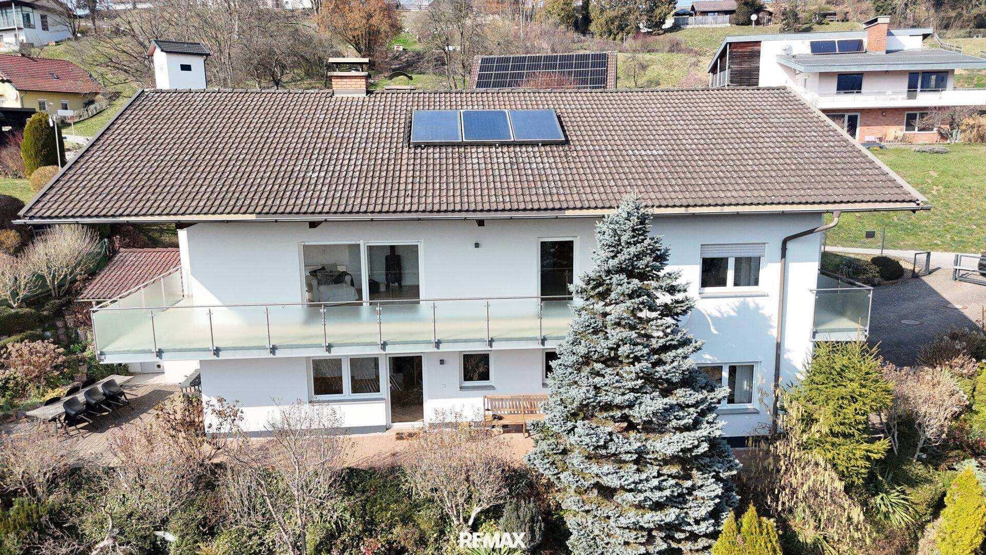 Luftaufnahme des Hauses mit Solarpaneelen auf dem Dach und umgebender Vegetation im Frühling.