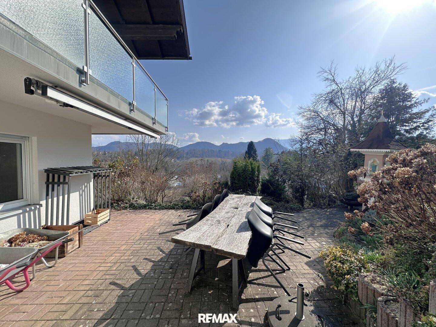 Große gepflasterte Terrasse mit Esstisch und atemberaubendem Bergblick unter blauem Himmel.